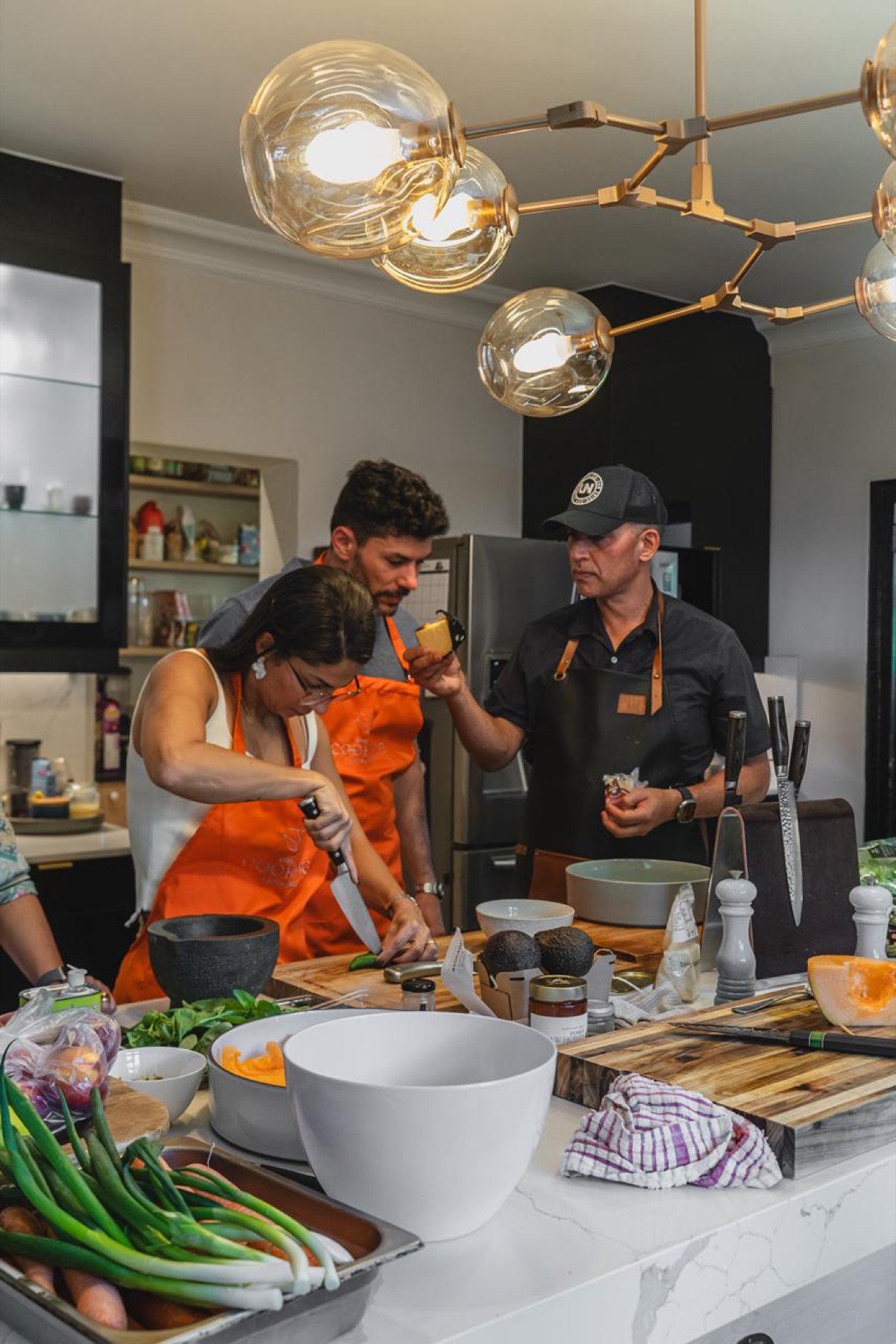Convidada prepara ingredientes enquanto Reuben Riffel conduz a experiência culinária